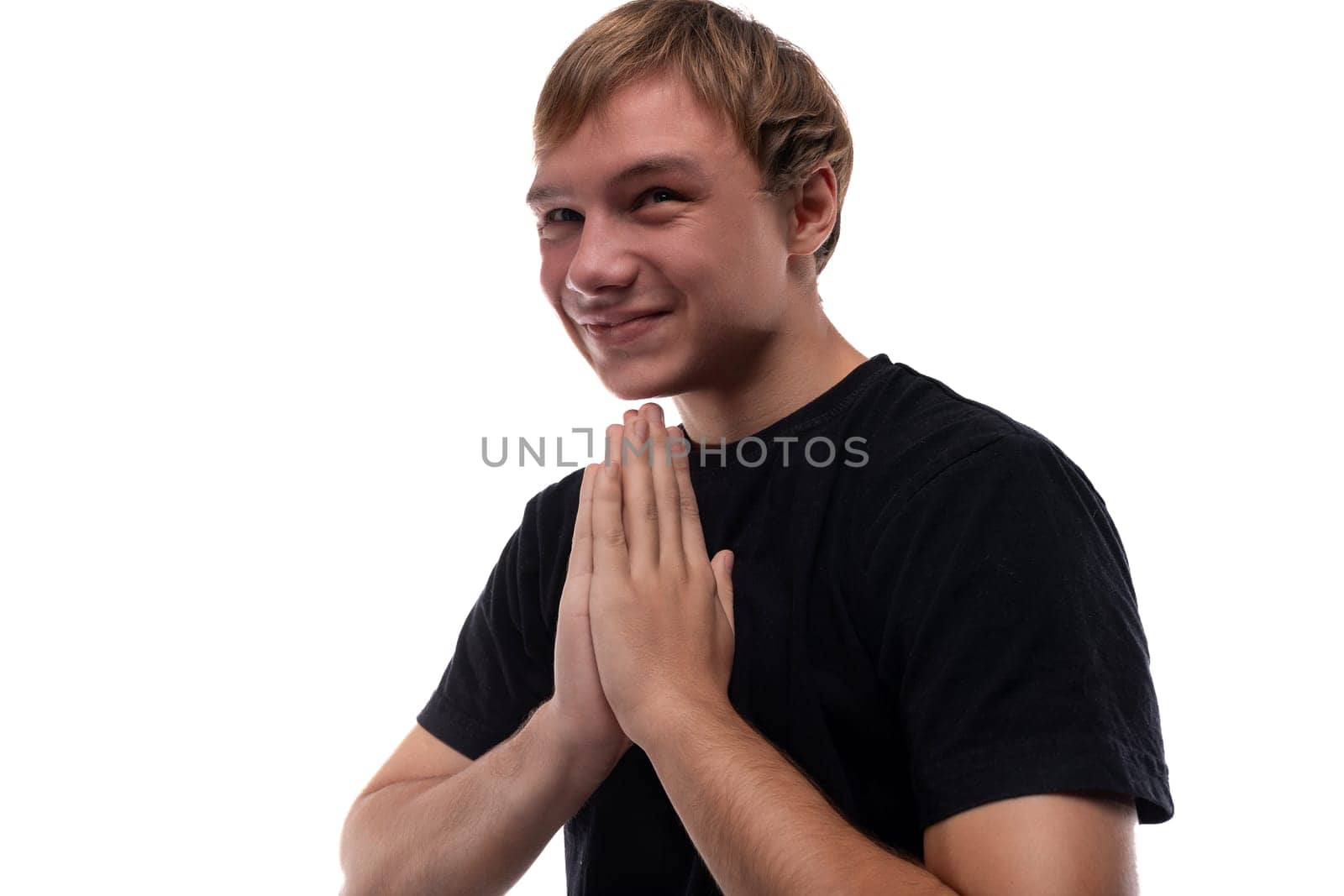 Blonde teenager dressed in a basic t-shirt rejoices on a white background.
