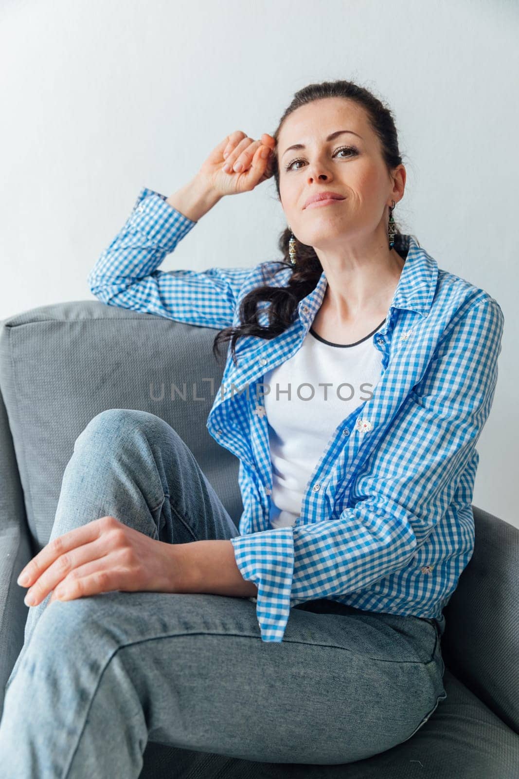 Beautiful brunette woman posing in armchair in bright room