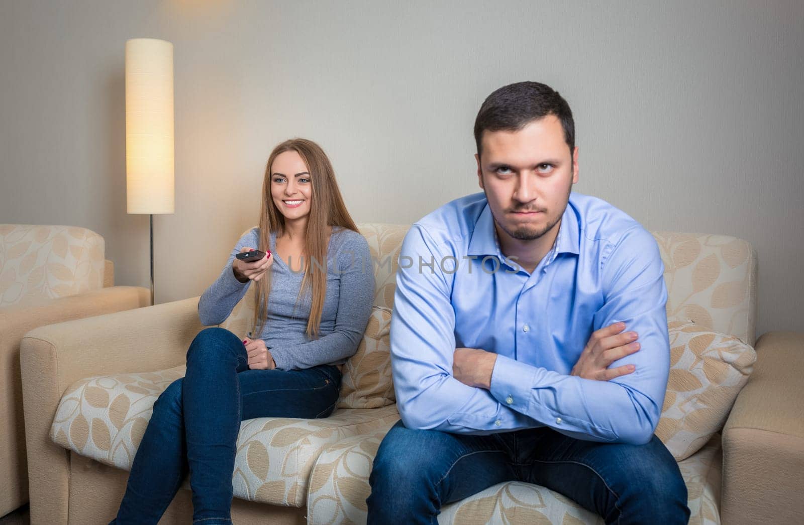 Portrait of couple sitting on sofa watching television. by nazarovsergey