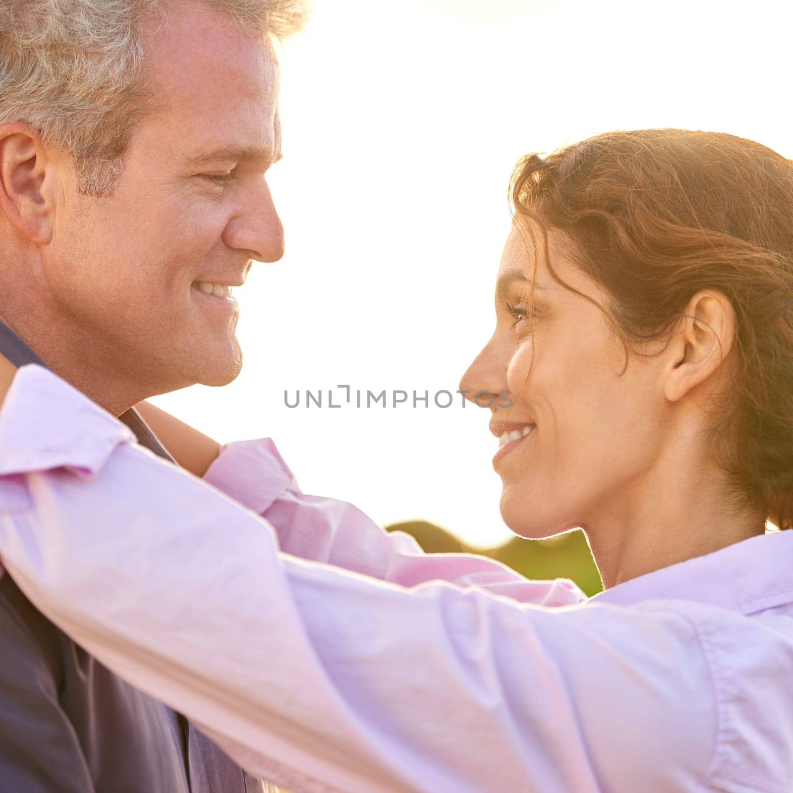 Old couple, smile and embrace at sunset with love, trust and support in marriage and retirement. Happy, woman and care for partner on holiday with freedom, health and wellness at the beach for cruise.