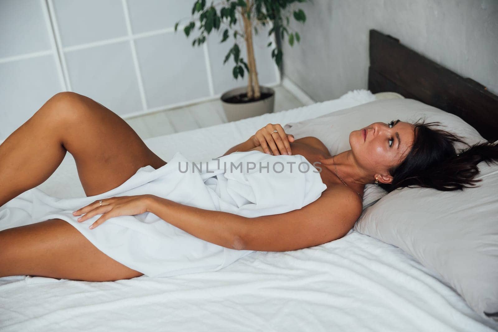 Brunette in lingerie lying on bed in room by Simakov