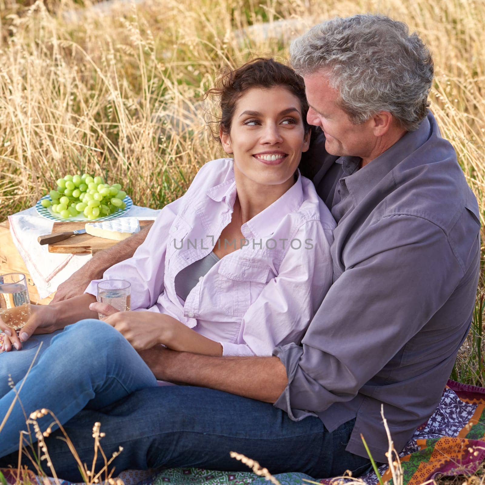 Mature couple, date and picnic in park to relax with love, care or support in marriage. Outdoor, man and embrace woman on grass in nature with food, drinks or celebration together on vacation.