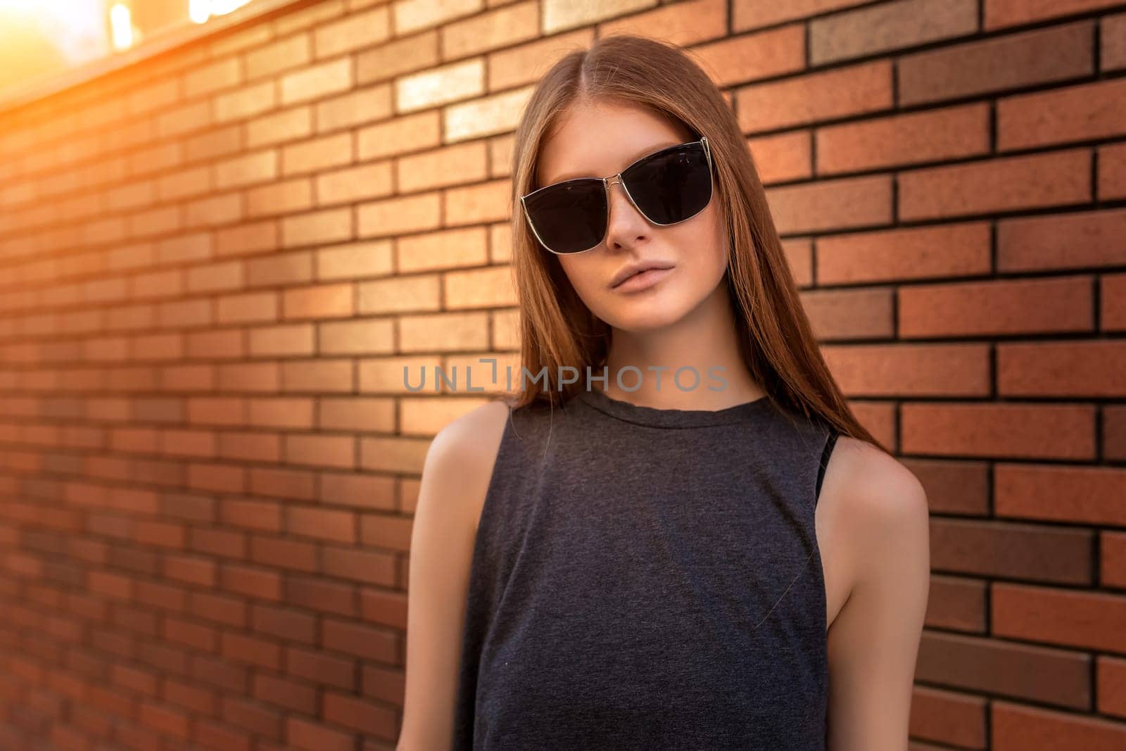 Portrait of Young Woman on Brick Wall Background. Trendy Urban Fashion Concept. Closeup
