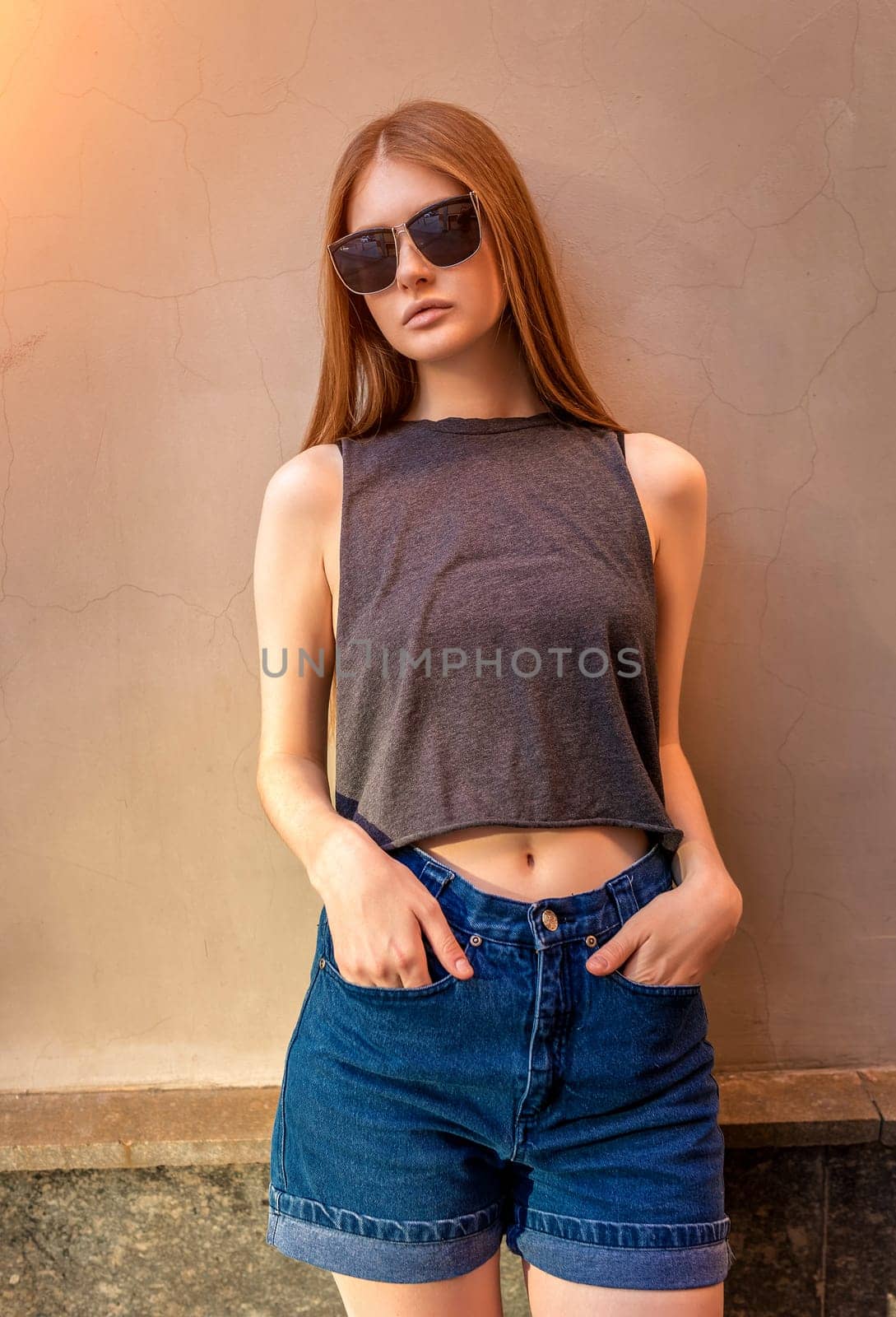 Portrait of Young Woman with Hands in Pockets on Wall Background. Trendy Urban Fashion Concept