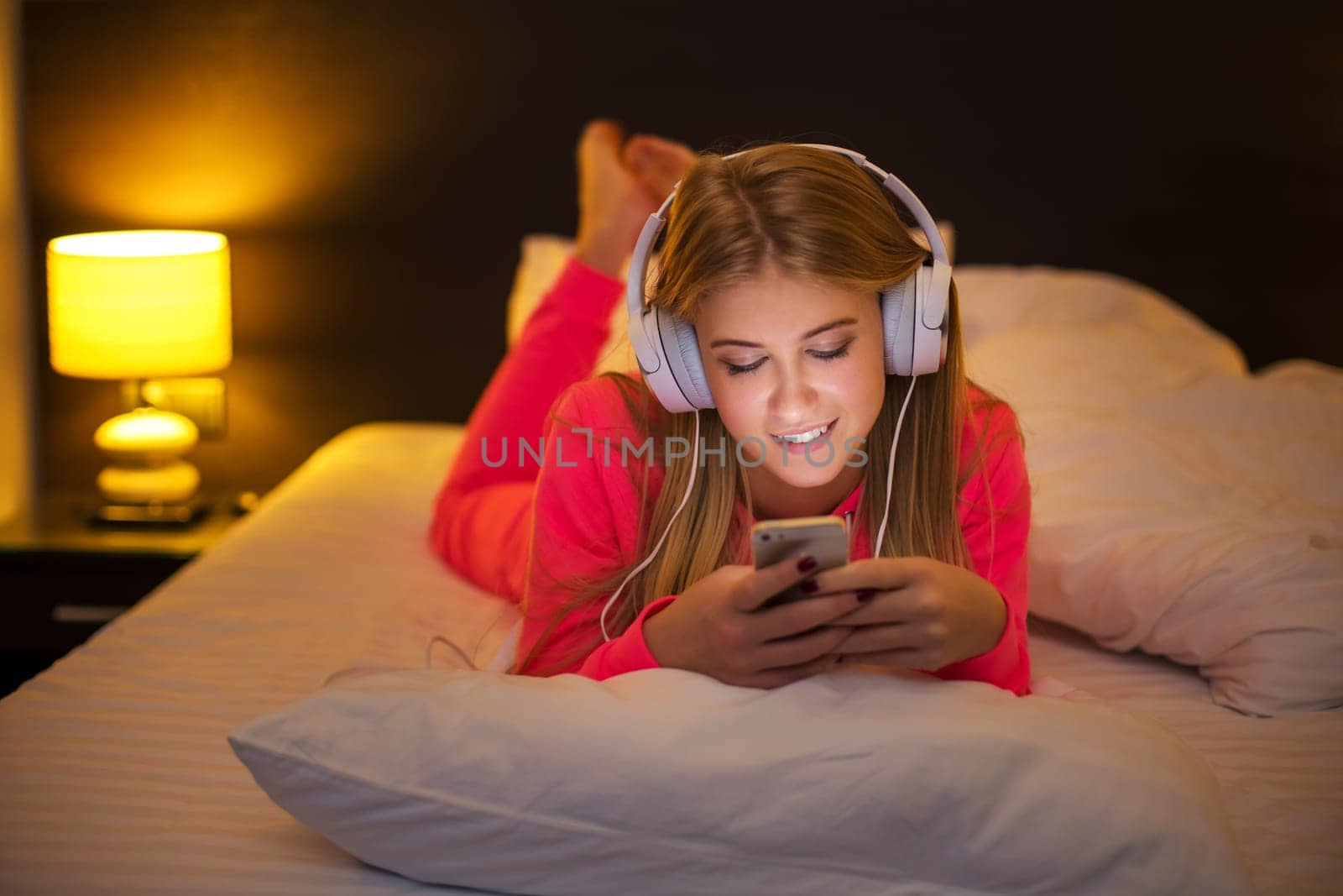 Young women listening to the music from smartphone on bed by nazarovsergey