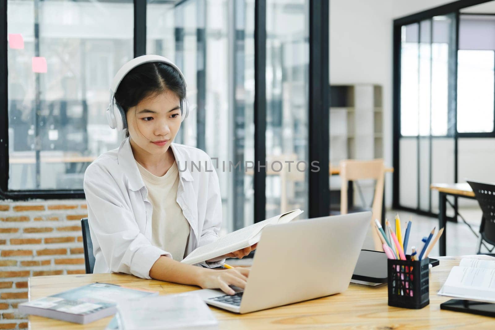 Online education, e-learning. Young collage student using computer and mobile device studying online. Asian young student online learning class study online video call zoom teacher.