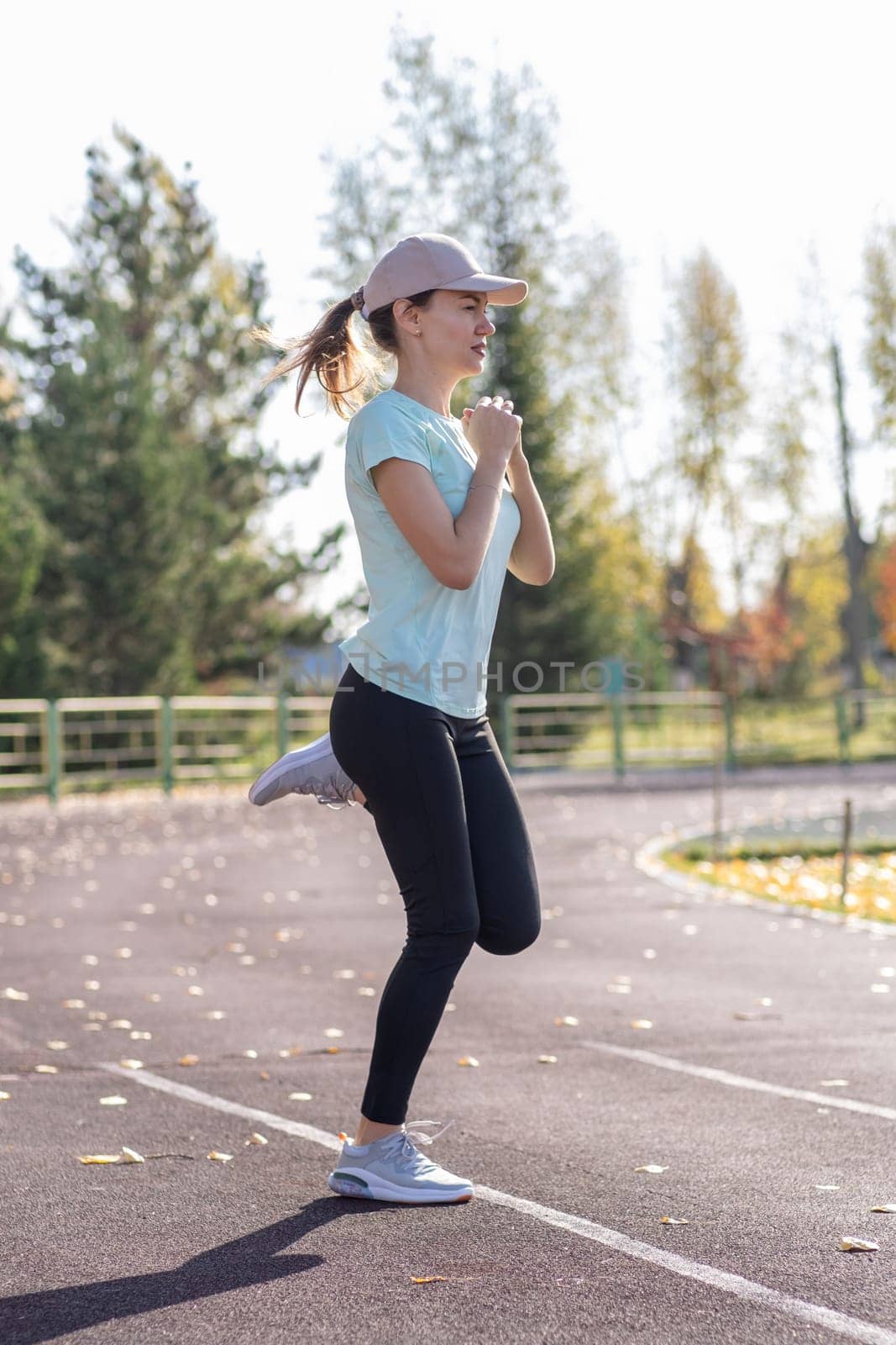 A young beautiful woman in sportswear plays sports at a local stadium by AnatoliiFoto