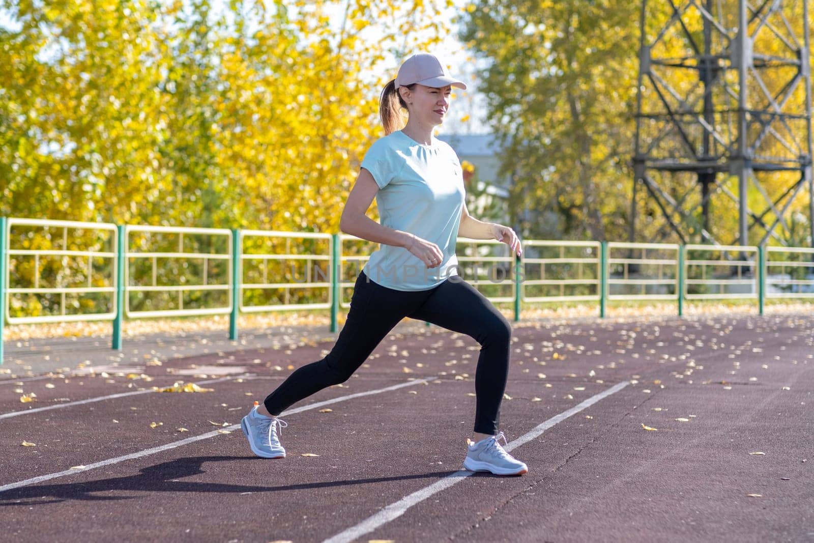 A young beautiful woman in sportswear plays sports at a local stadium by AnatoliiFoto