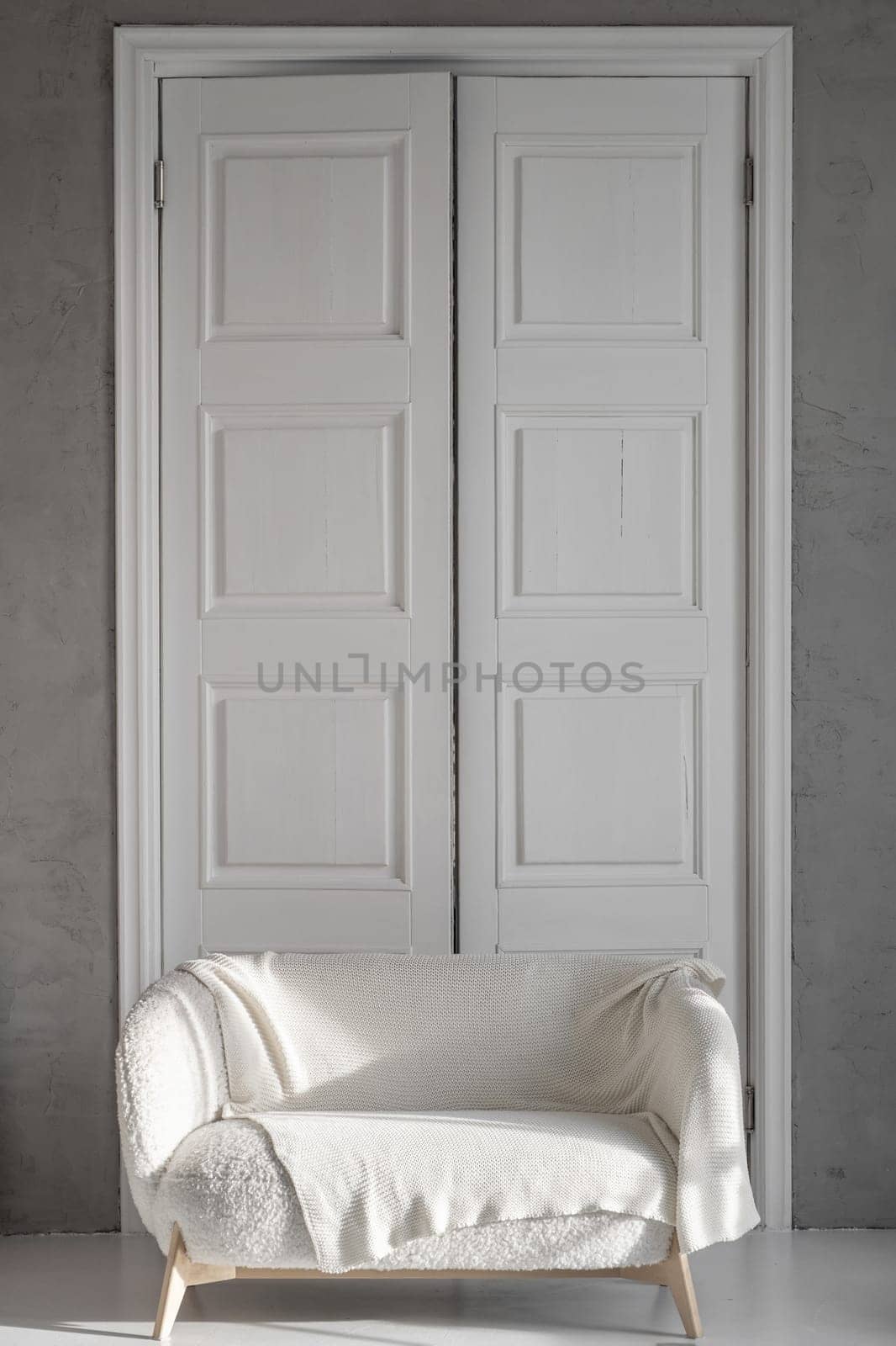 A beautiful room with tall white wooden doors and a white sofa against by AnatoliiFoto