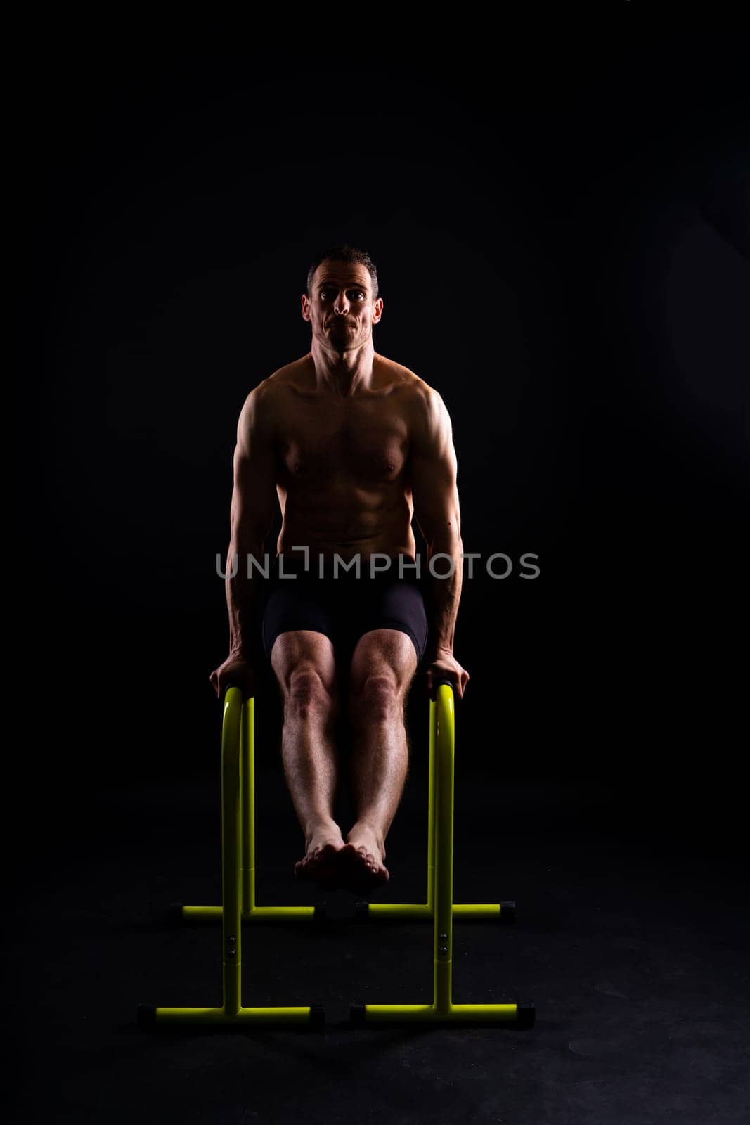 Male gymnast performing handstand on parallel bars, studio shot by Zelenin