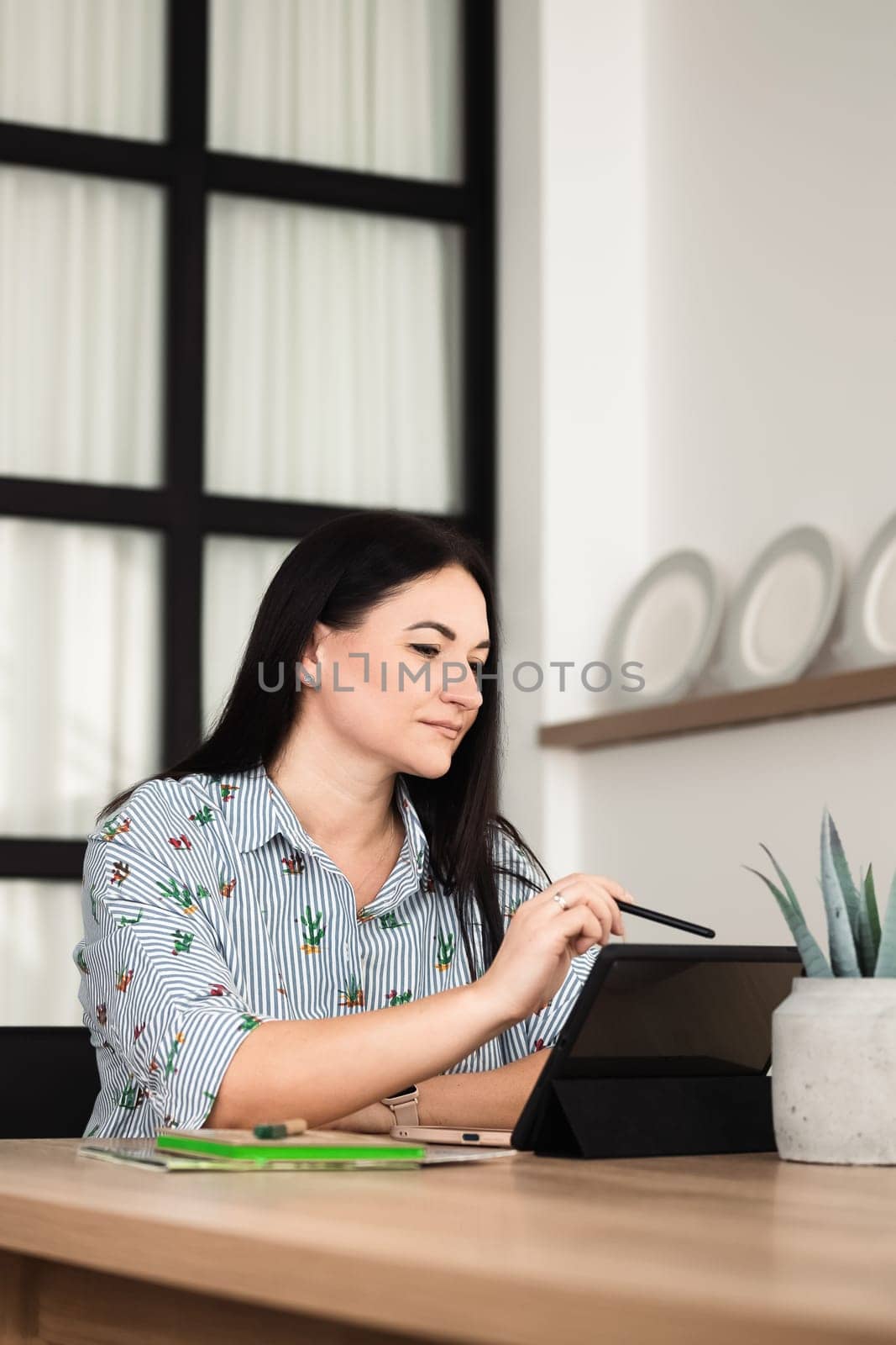 In the office, a young brunette girl is working on a tablet