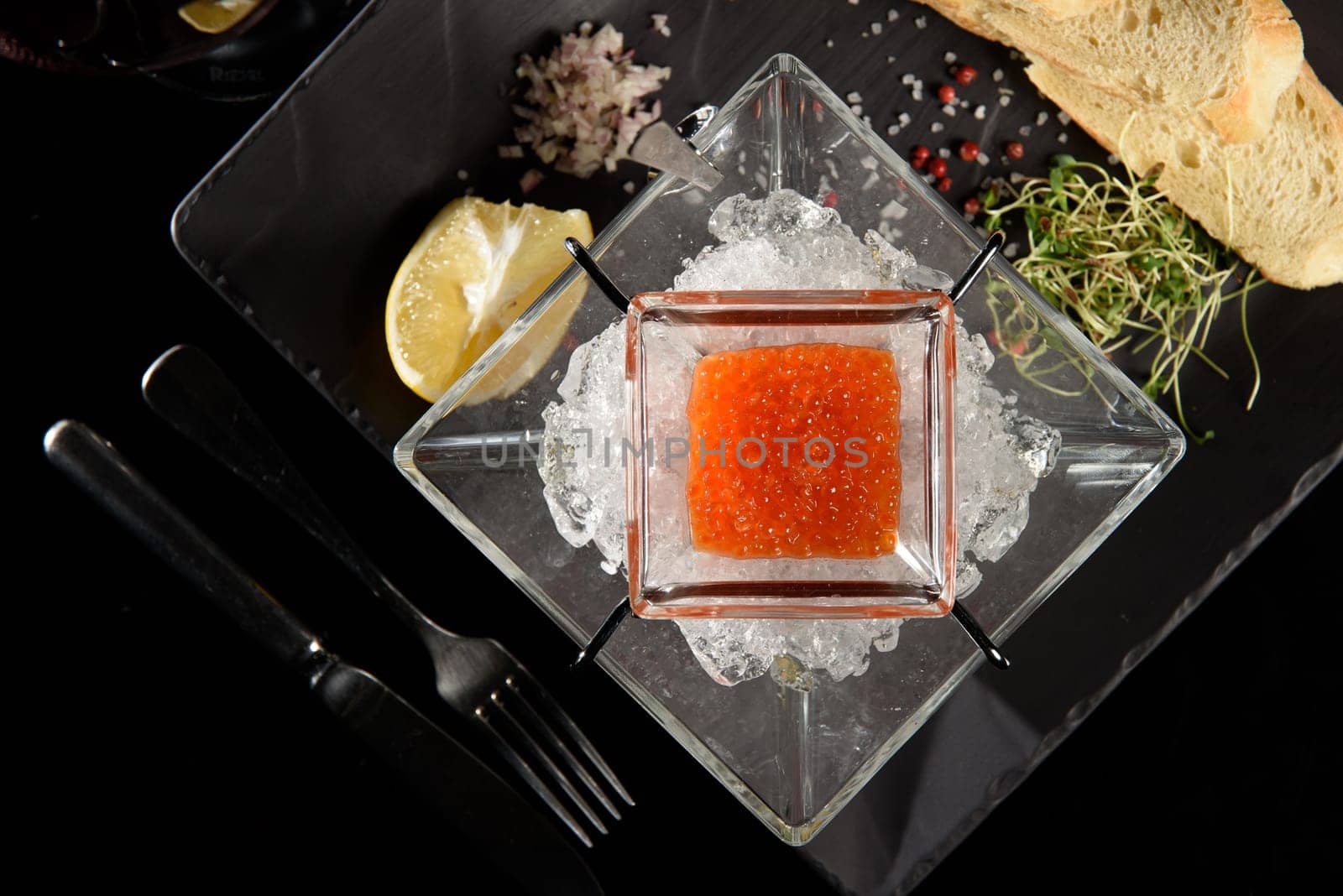 salmon fish caviar, on ice, with croutons, lemon, on a transparent dish, on a dark background by Ashtray25