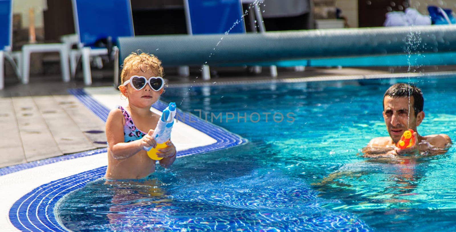 A child and his father play with a water pistol in the water. Selective focus. Kid.