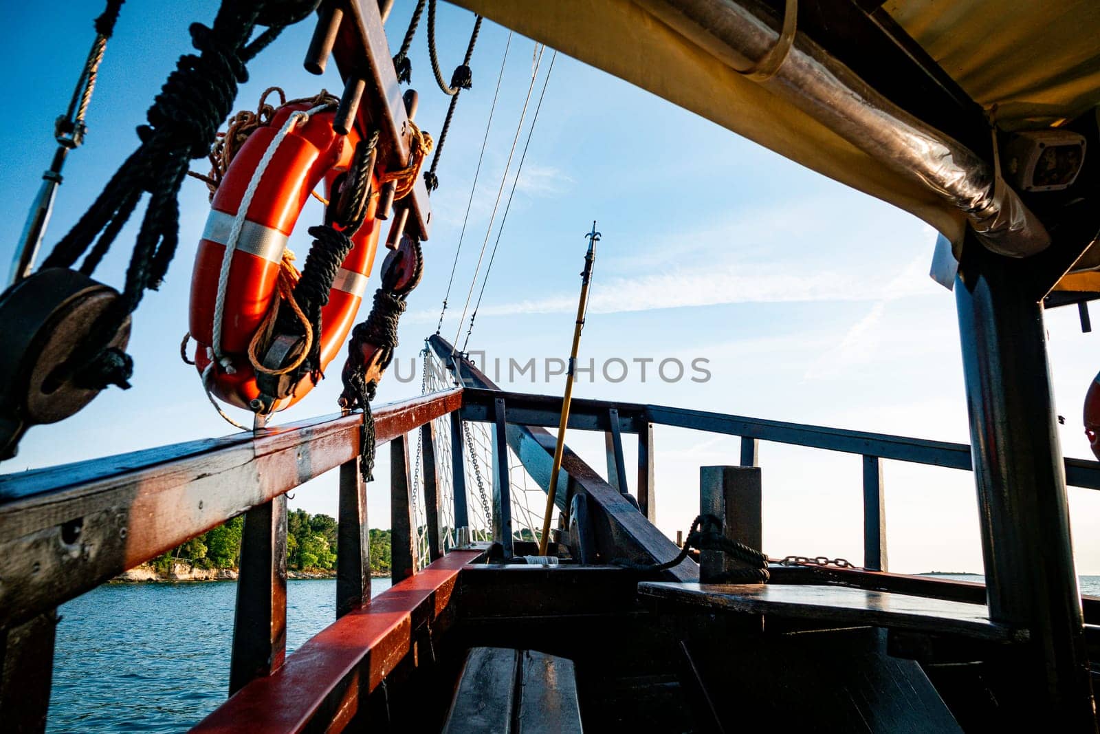 a beautiful old wooden boat with fishing nets and red lifebuoys with a tropical island in the background