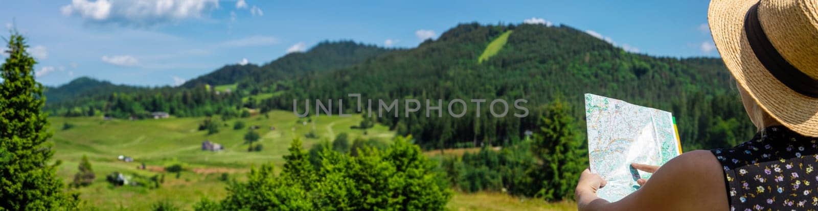 A woman in the mountains looks at a map. Selective focus. Nature.