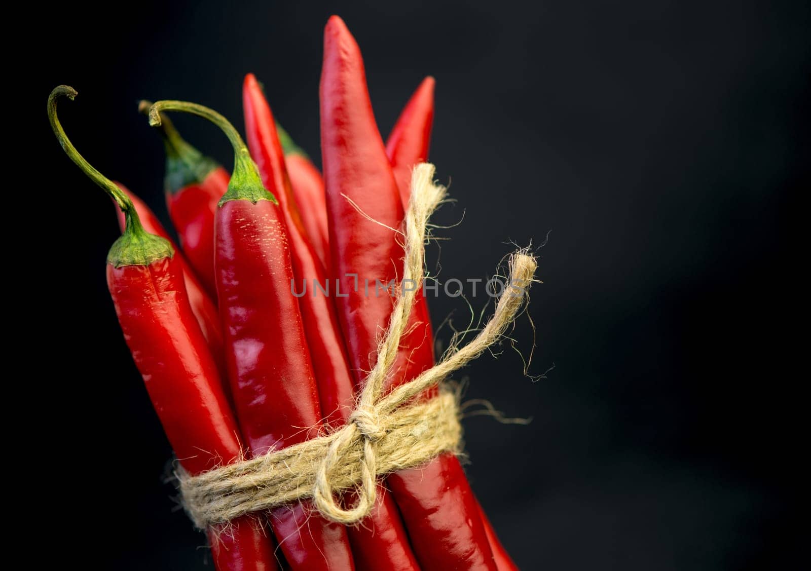 Chili pepper isolated on a black background. Knitted hot chili pepper tied with a rope. Chili hot pepper clipping path by aprilphoto