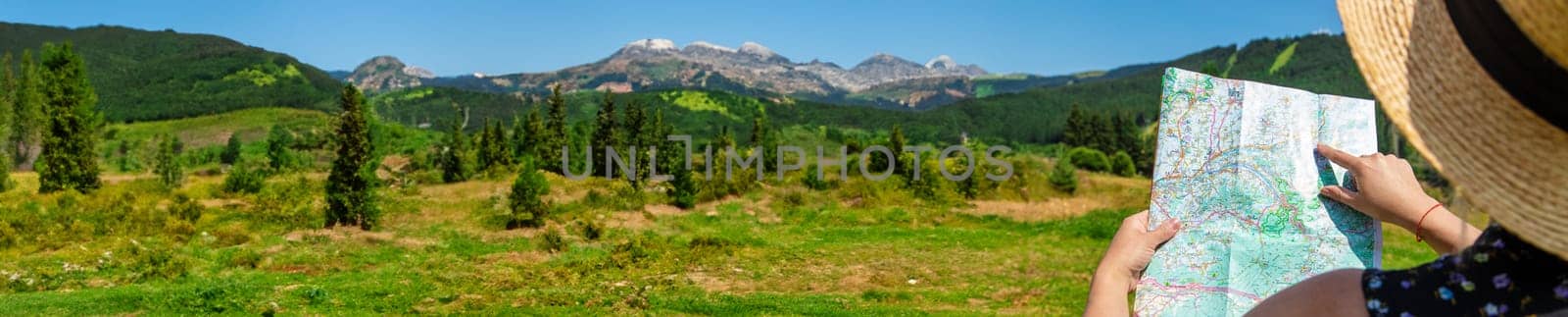 A woman in the mountains looks at a map. Selective focus. Nature.