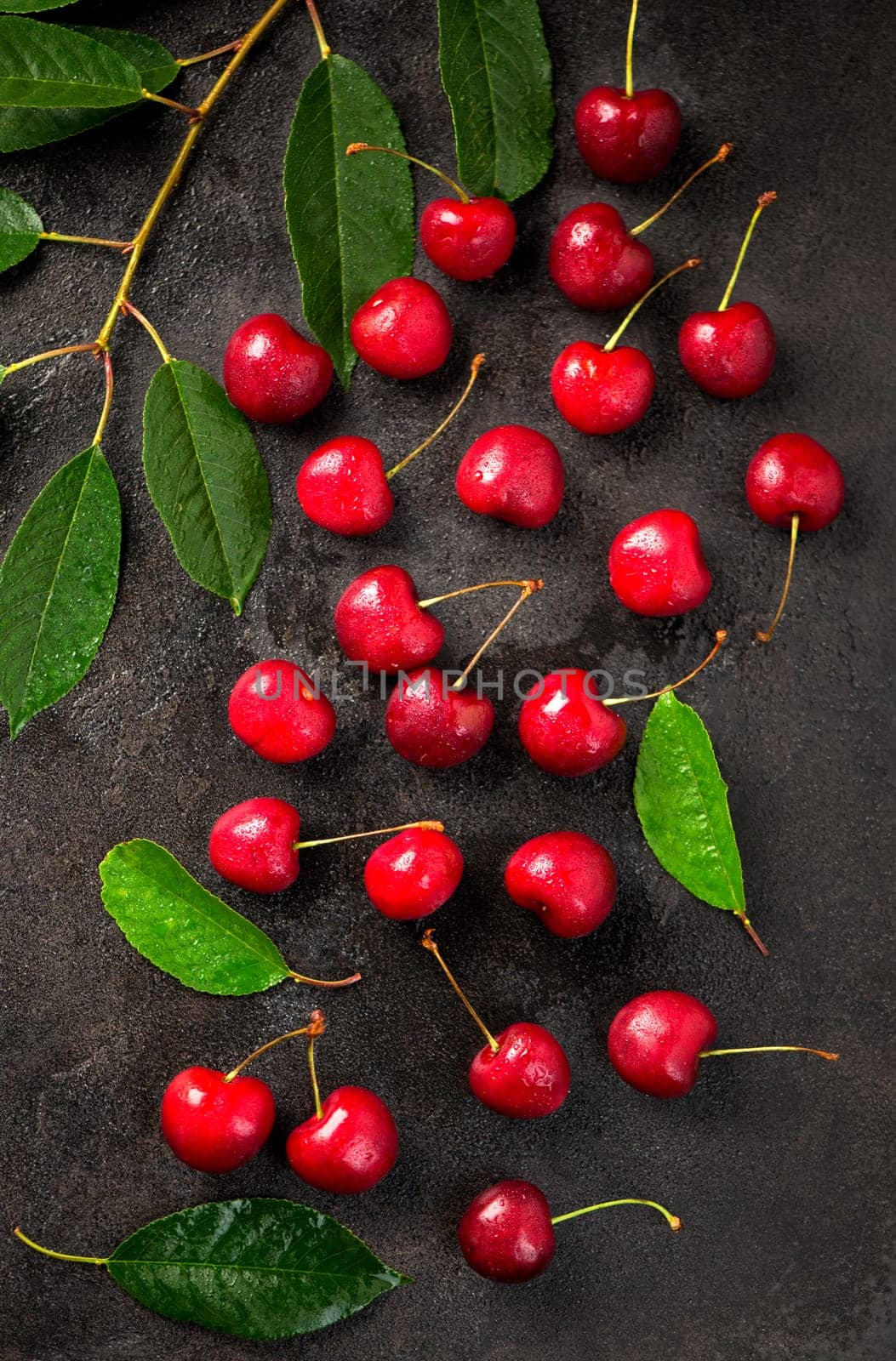 Ripe sweet cherry berry with leaves on a black wooden board. by aprilphoto
