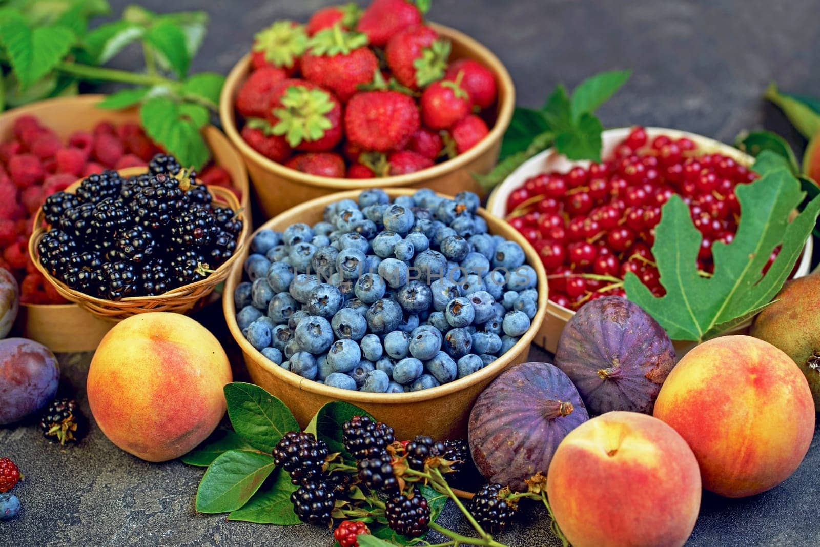 berry mix. A variety of summer berries - raspberries, strawberries, blueberries, cherries, currants, plums - in cups on a wooden table by aprilphoto