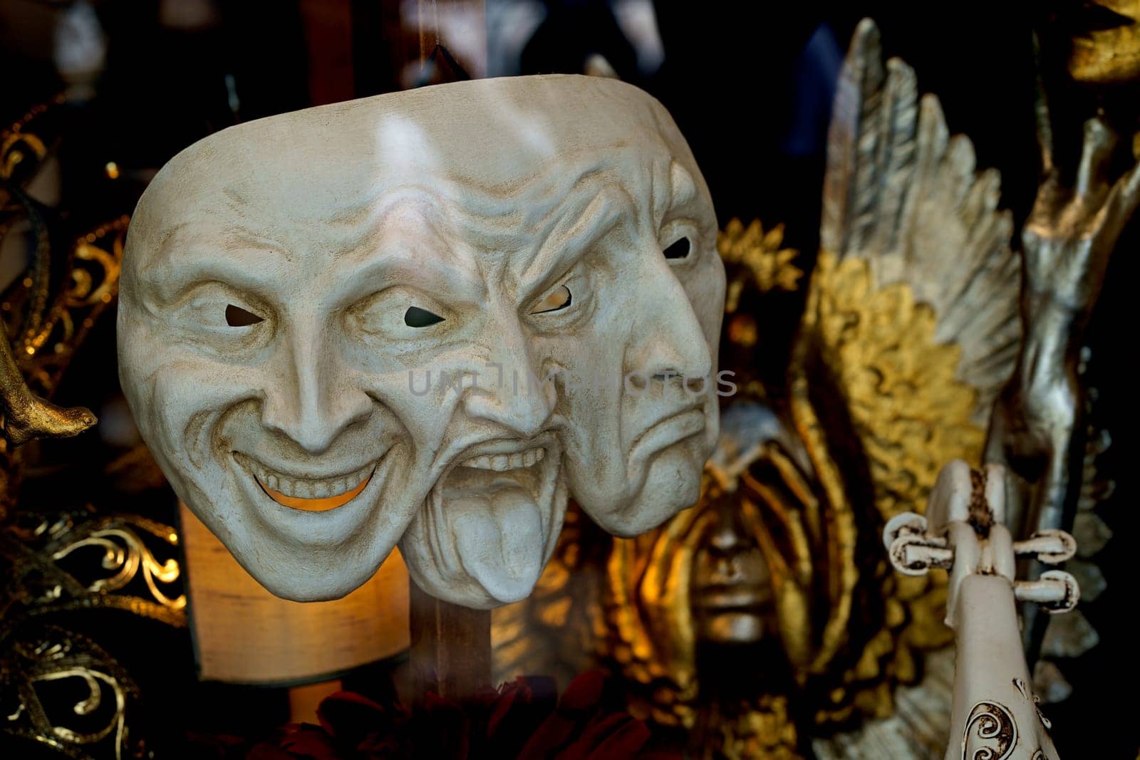 venetian mask expresses joy, irritation and sadness standing in a store window on a black background by aprilphoto