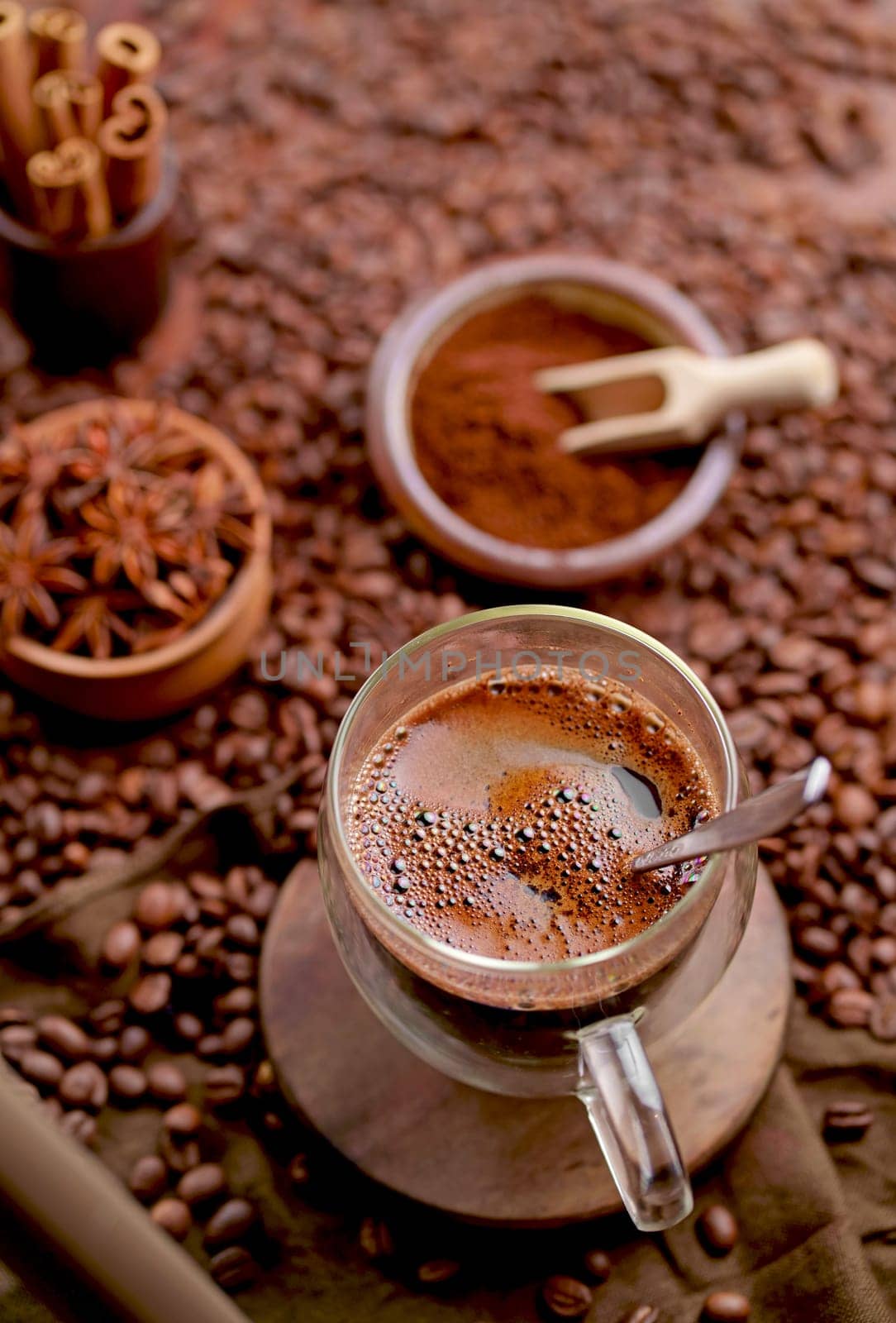 transparent stylish cup of coffee and grains. A cup of coffee among selected and calibrated Arabica coffee beans scattered on a napkin, table, blended, top view by aprilphoto