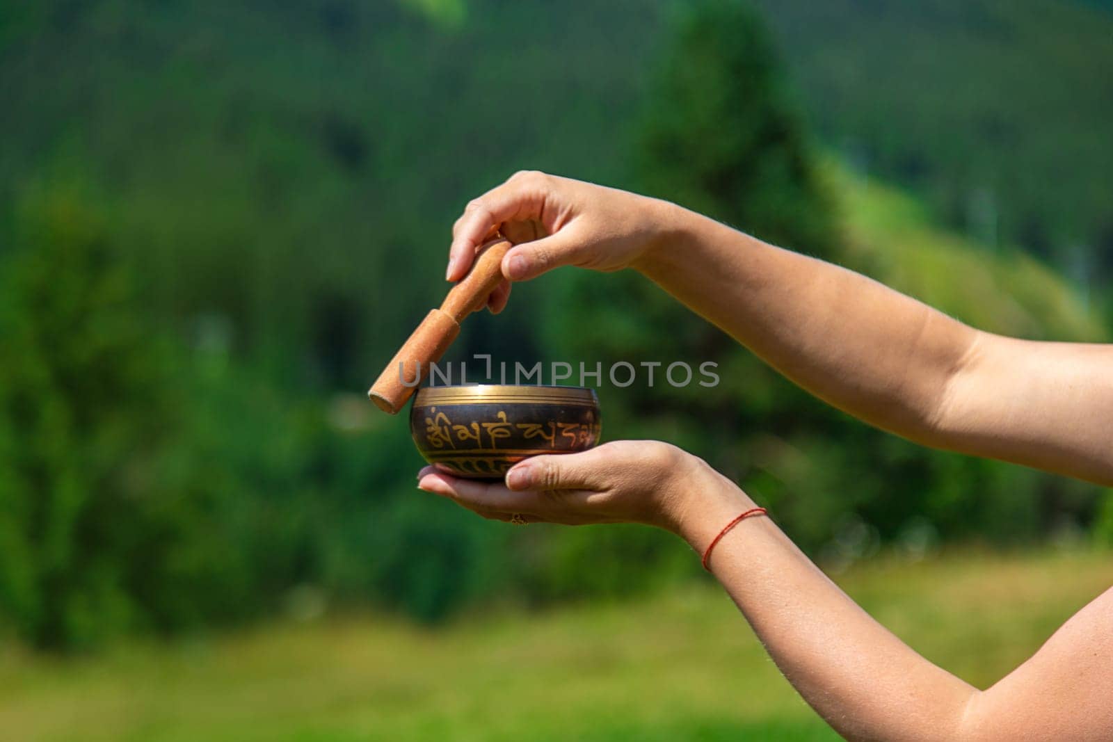 A woman holds a singing bowl in her hands. Selective focus. Nature.