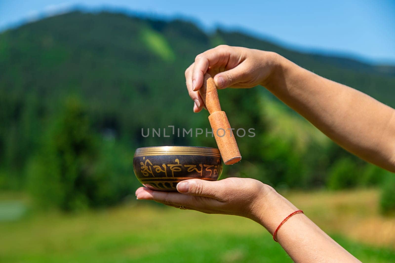 A woman holds a singing bowl in her hands. Selective focus. Nature.