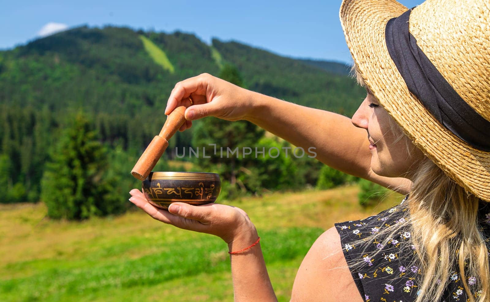 A woman holds a singing bowl in her hands. Selective focus. Nature.