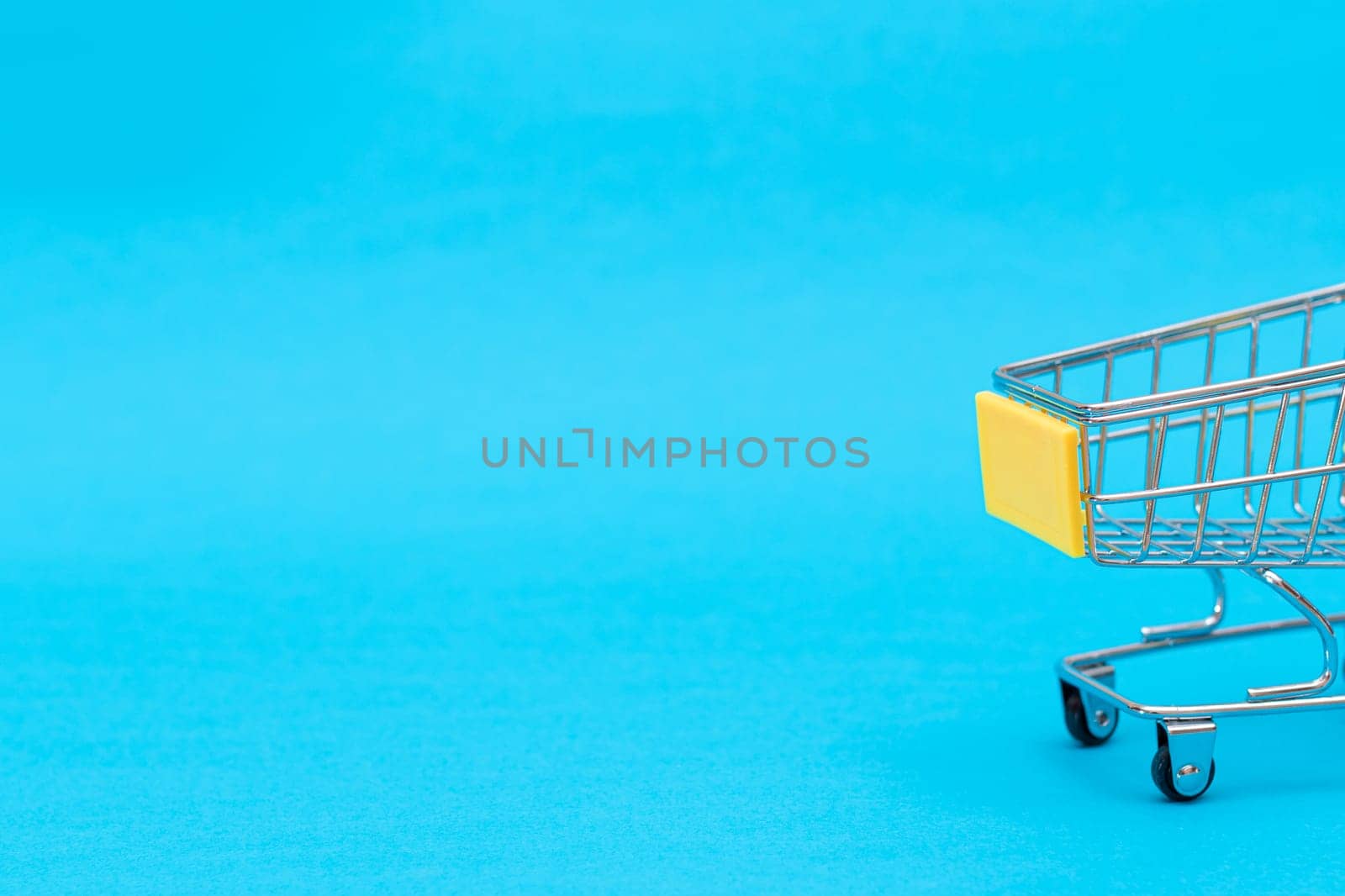 Empty Yellow Shopping Cart on Blue Background. Shopping, Trade and Market Concept