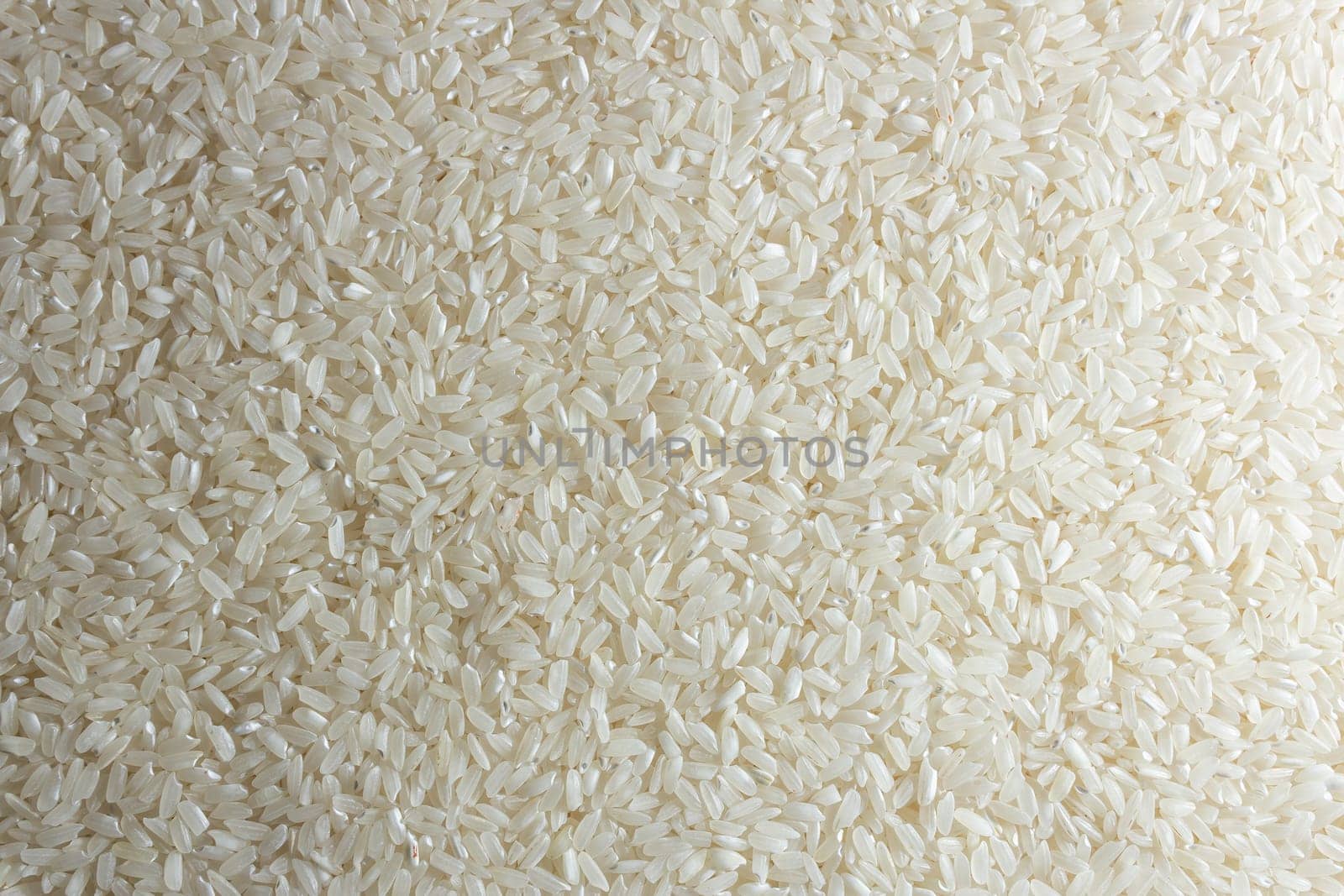 Dry Uncooked White Rice Background - Top View, Flat Lay. Scattered Raw Long Grain Rice. Asian Cuisine and Culture. Healthy Eating Ingredients. Diet Food