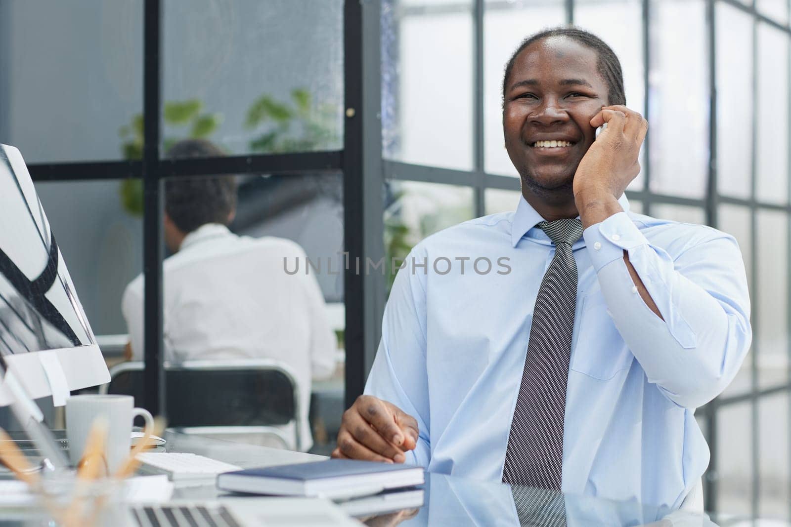 a man at a workplace at a table in front of a computer speaks on the phone by Prosto