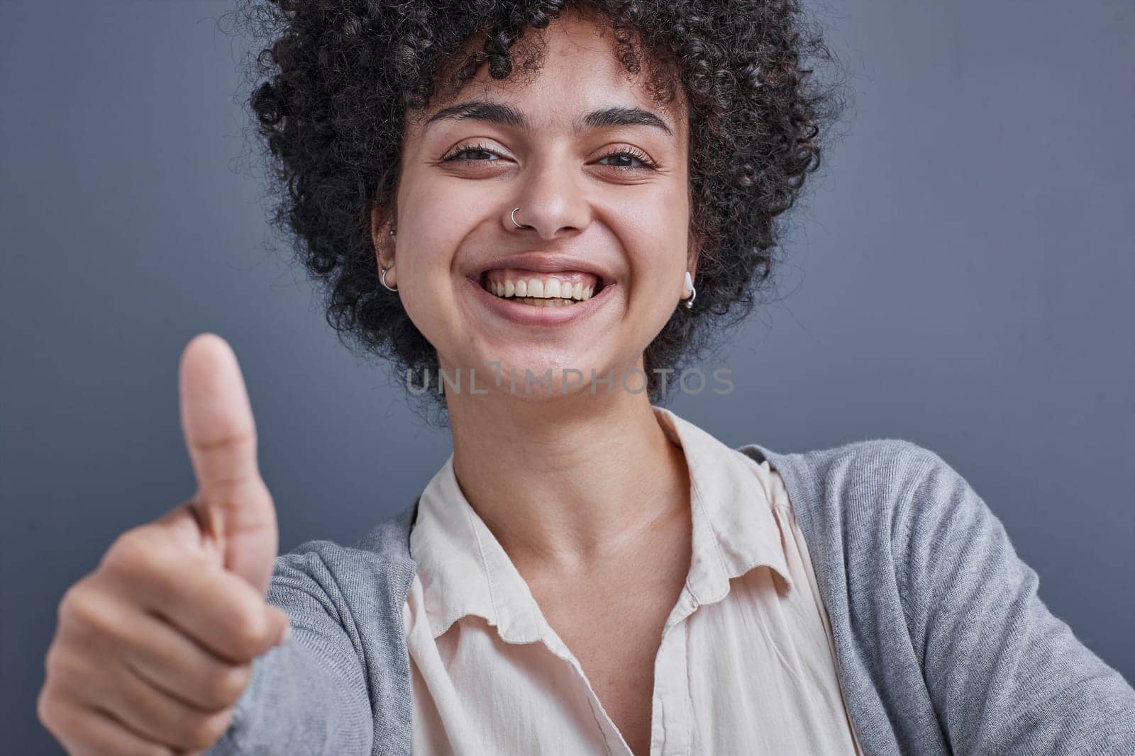 girl on a gray background smiling and showing a raised thumb by Prosto