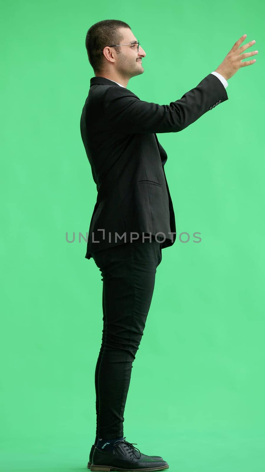 young man in full growth. isolated on green background pointing with finger by Prosto