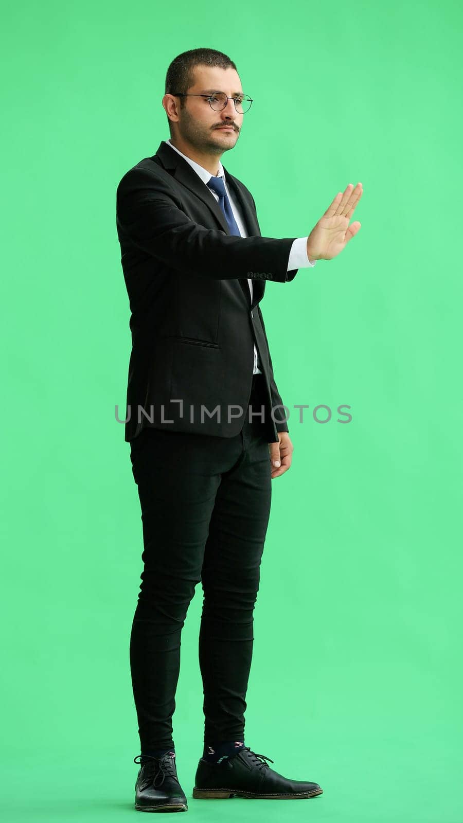 young man in full growth. isolated on green background shows stop sign with hand by Prosto