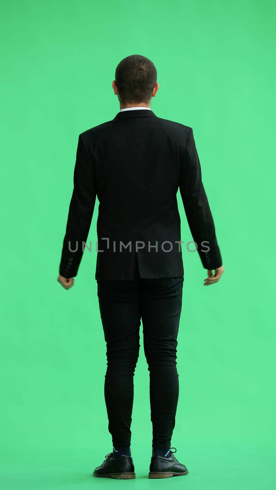 young man in full growth. isolated on green background. view from the back.