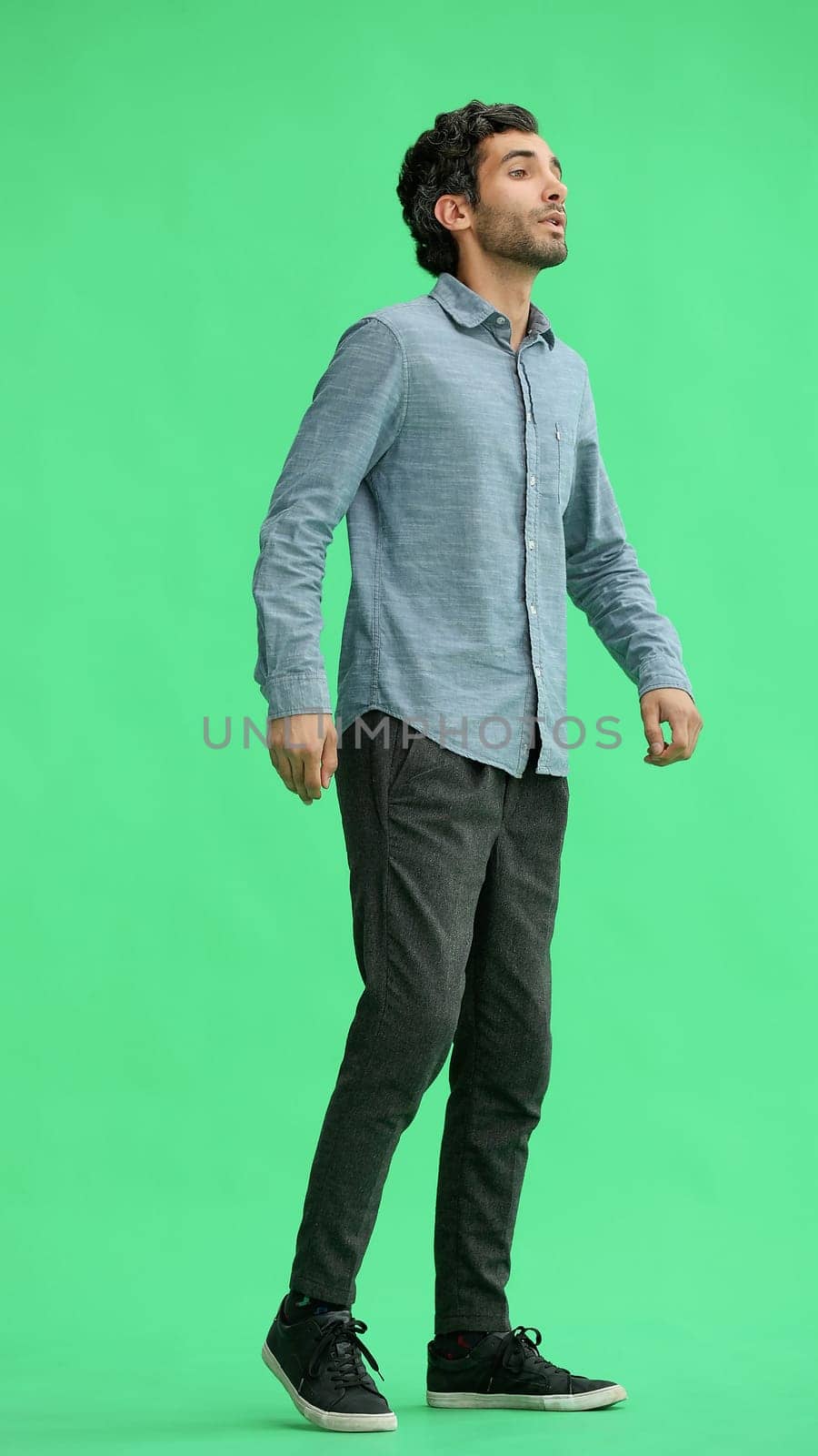 full-length portrait of a young man. standing isolated on green background.