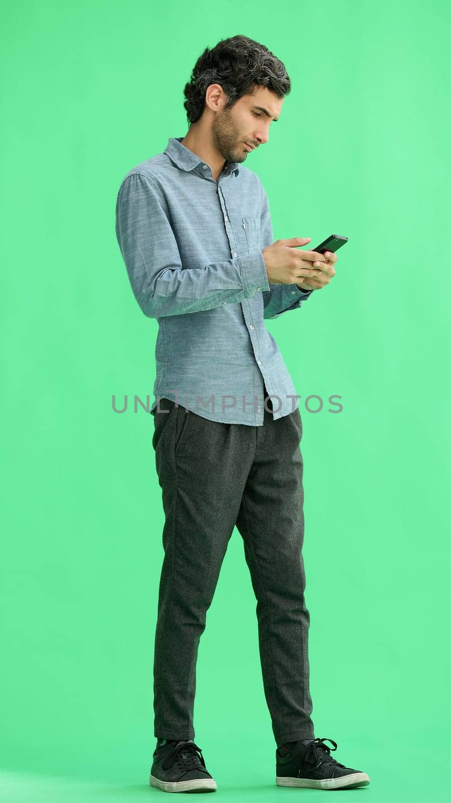 young man in full growth. isolated on green background taking selfie.