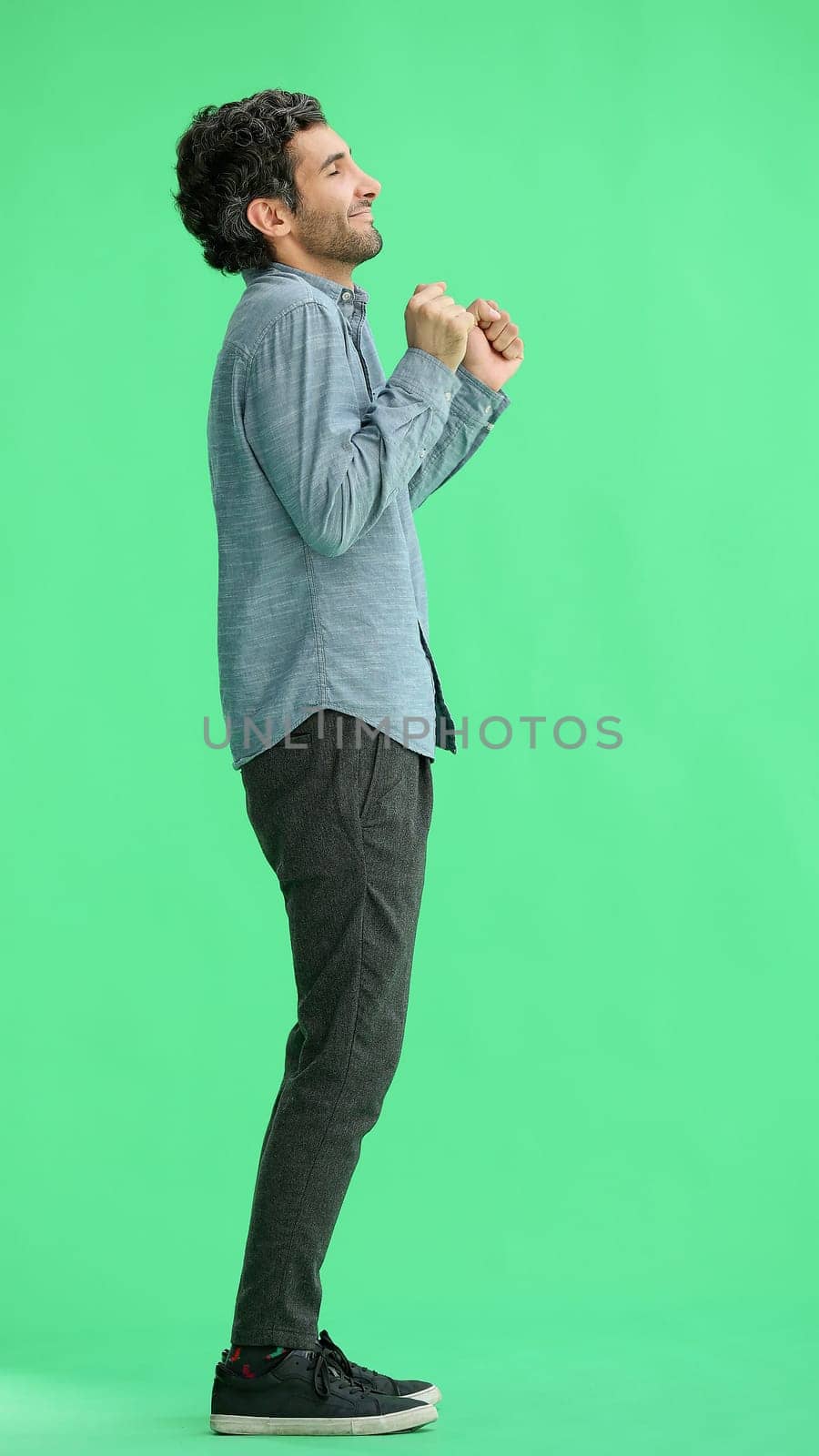 man isolated on a green background shows with his hands a sign of what to expect by Prosto