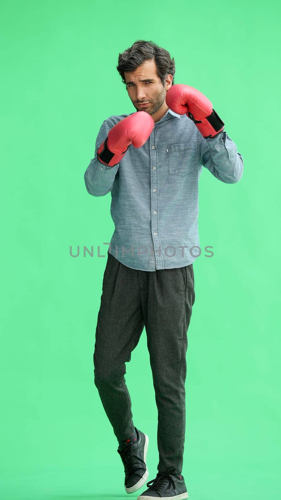 man in full growth. isolated on a green background in business clothes with boxing gloves by Prosto