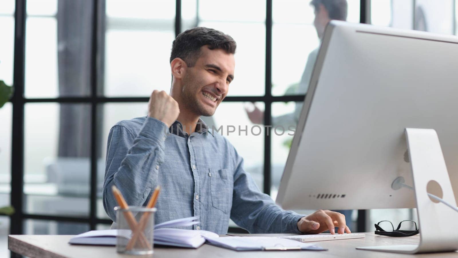 Happy businessman rejoices at success in the workplace in the office, looks up with a euphoric expression on his face. by Prosto