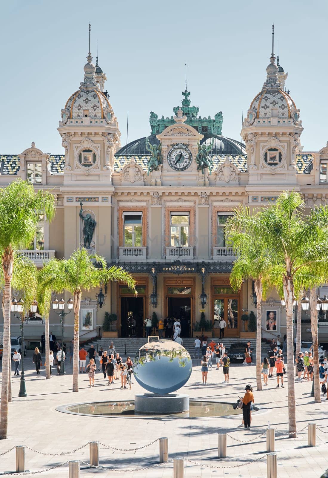 Monaco, Monte-Carlo, 21 October 2022: Square Casino Monte-Carlo at sunny day, wealth life, tourists take pictures of the landmark, pine trees, blue sky. High quality photo