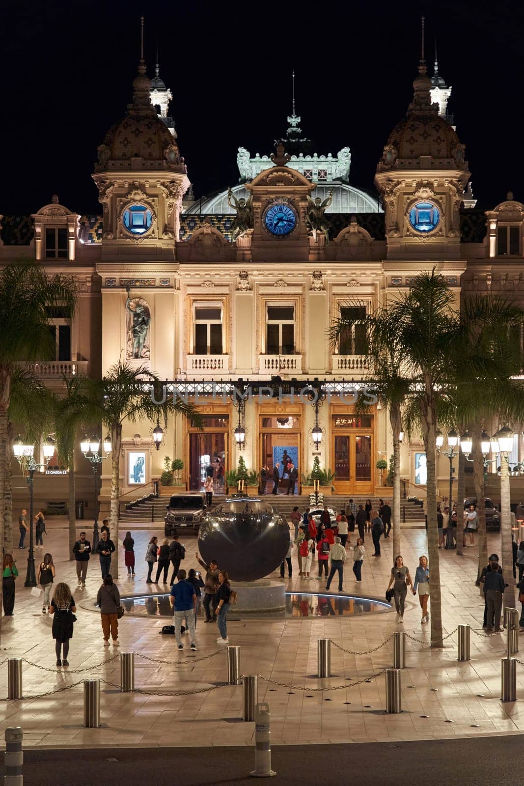 Monaco, Monte-Carlo, 12 November 2022: The famous square of Casino Monte-Carlo is at dusk, attraction night illumination, luxury cars, players, tourists, splashes of fountain. High quality photo