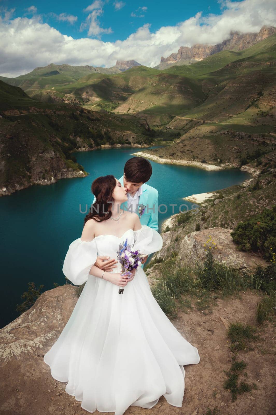 A beautiful couple kisses and hugs against the background of a mountain river and an epic sky. wedding happy couple on the lake