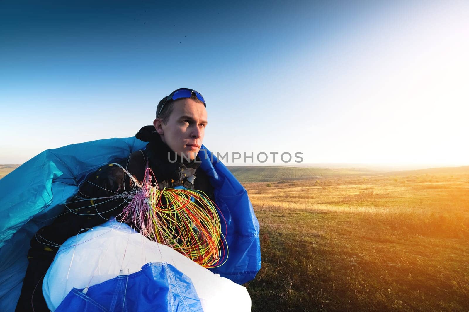 guy holds the lines of a paraglider in his hands close-up. A male paraglider carries a paraglider to a pasture. The pilot checks the paraglider's lines to ensure they are not damaged. by yanik88