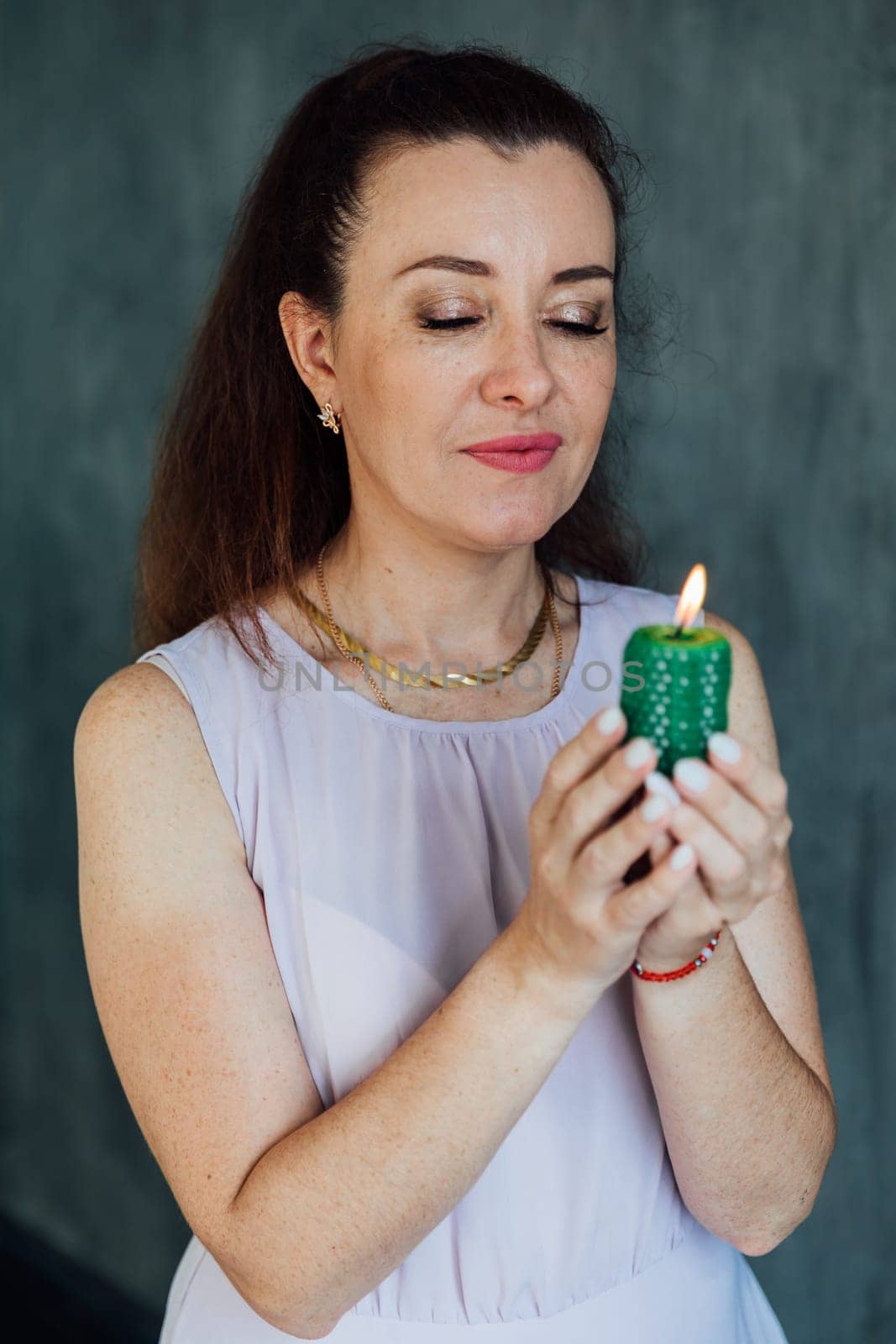 Beautiful brunette woman holding a green candle in her hands by Simakov