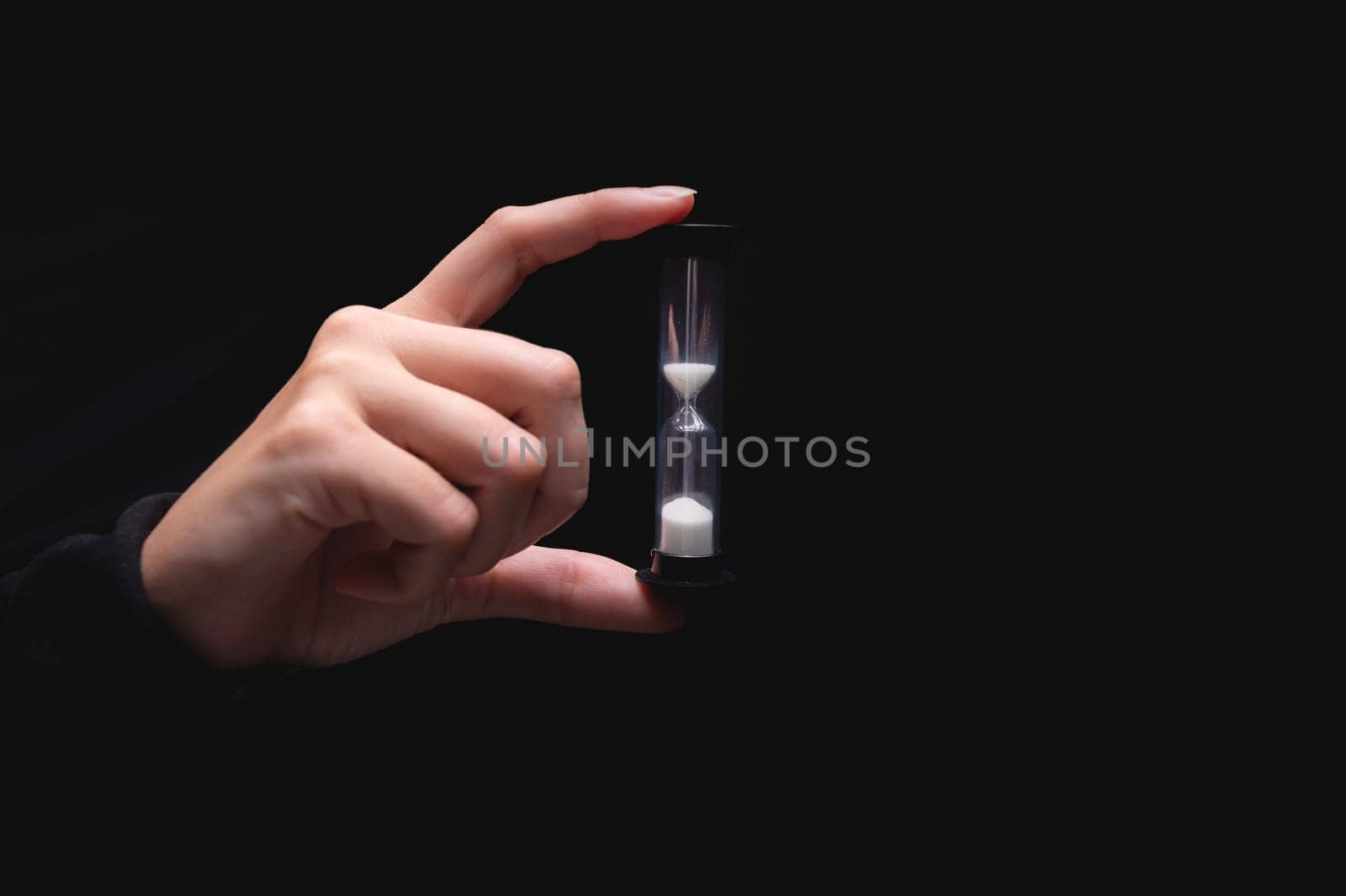 Close-up of a woman holding an hourglass. Time goes by and time runs out. Countdown timer.