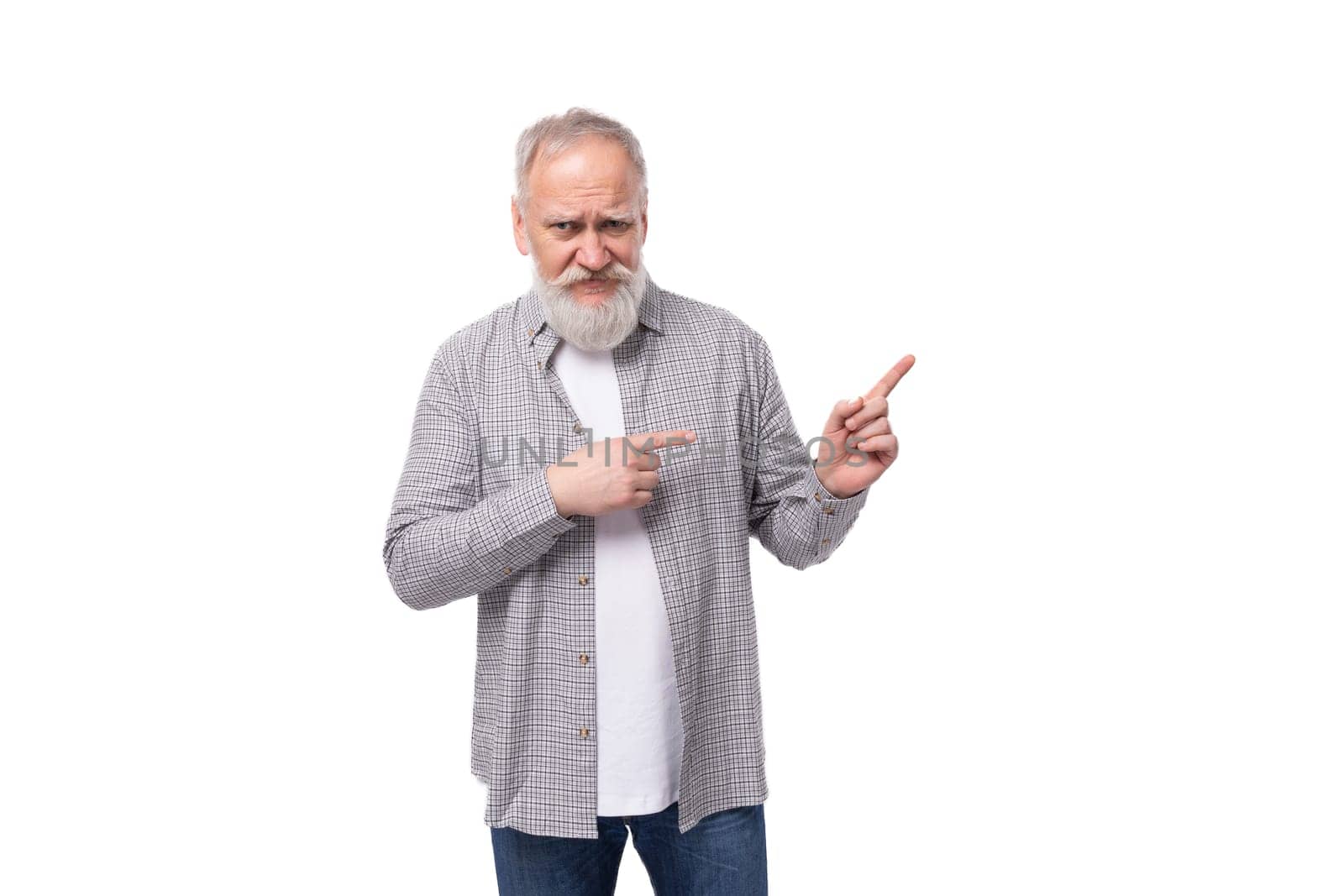 well-groomed senior man with a gray beard and mustache is dressed in a plaid shirt and jeans on a white background with copy space.
