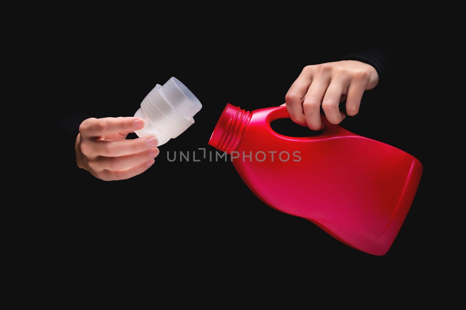 woman's hand pours cleaning product or bleach on a black background. Woman opened detergent, close-up, label mockup by yanik88