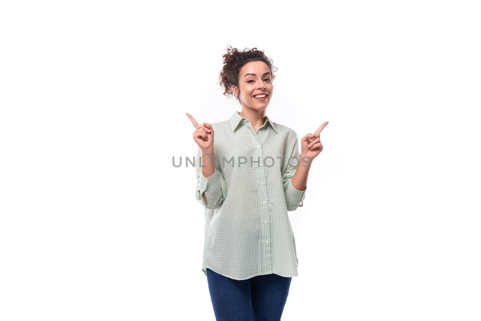 active confident beautiful black-haired curly woman with careless styling bun in a rurabka points with her hand and smiles.