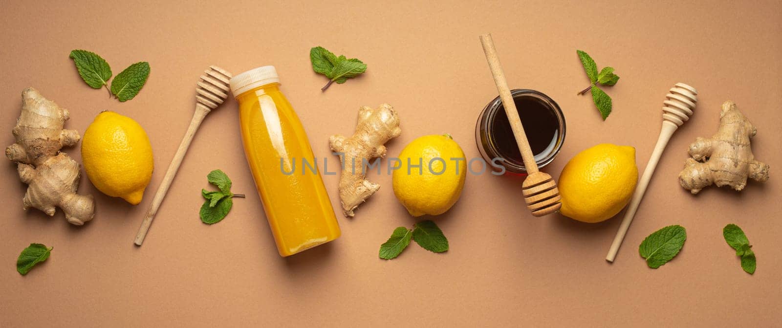Composition with detox drink, lemons, mint, ginger, honey in glass jar and honey wooden dippers top view. Food for immunity stimulation and against flu. Healthy natural remedies to boost immune system by its_al_dente